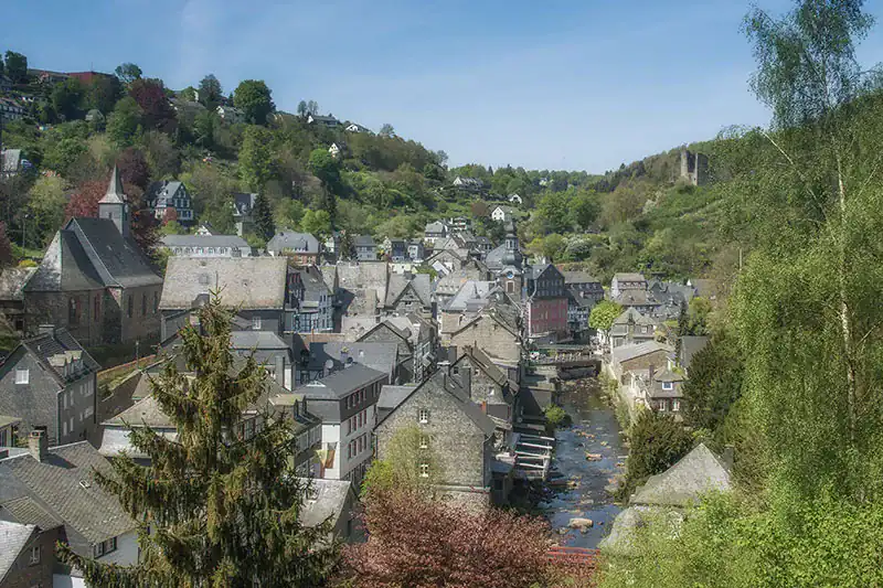 Alt: Charmantes Dorf in Köln mit historischen Gebäuden und malerischer Flusslandschaft.